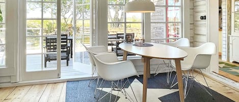 A dining area with a round table, white chairs, and a hanging light fixture.
