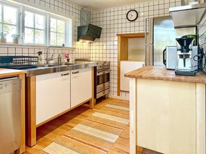 A kitchen with a dishwasher, stove, sink, and a coffee maker. - 5 Star Holiday Home in Borgholm (Borgholm)
