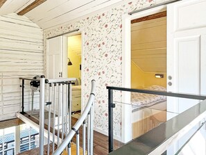 A staircase with metal railings leading to a bedroom with floral wallpaper and a bed. - 5 Star Holiday Home in Borgholm (Borgholm)