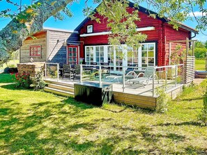 A red wooden cabin with a deck and a small pool, surrounded by a grassy yard and trees. - 5 Star Holiday Home in Borgholm (Borgholm)