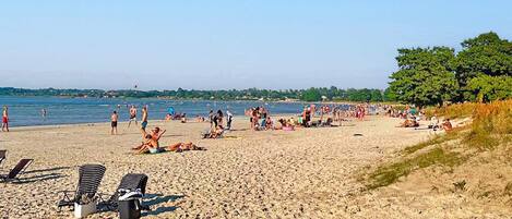 Una playa con tumbonas y gente relajándose.