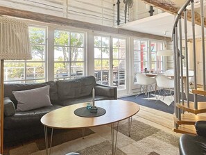 Un interior moderno con un sofá, una mesa redonda y una escalera en espiral.
