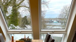 A dining area with a table set for two, a bottle of Henkell beer, and a box of wine glasses.