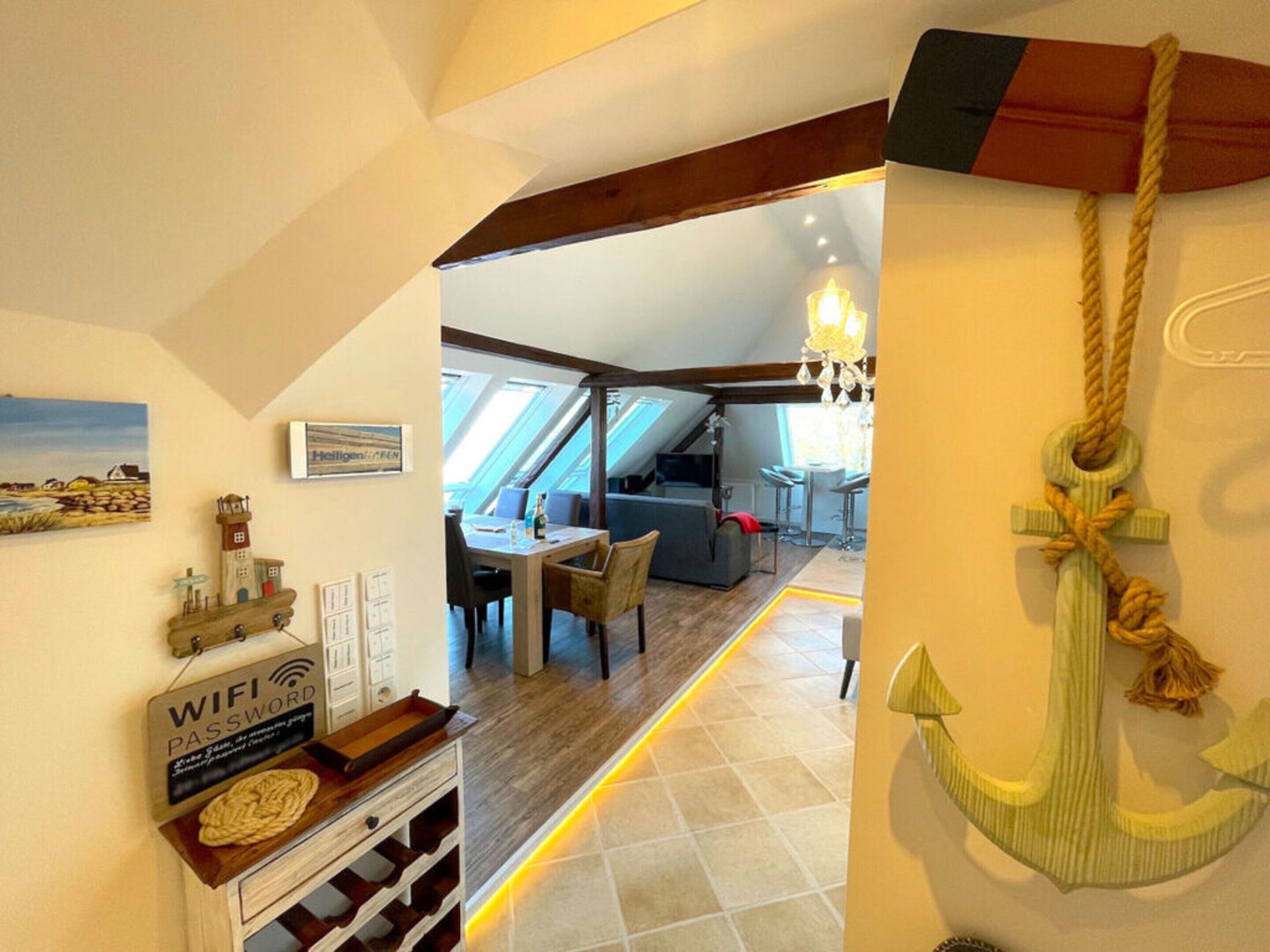Un intérieur chaleureux avec un coin repas, un escalier et une vue sur l’extérieur.