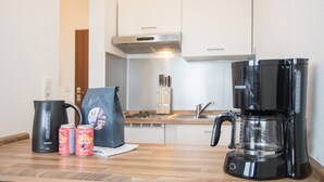 A kitchen with a coffee maker, a kettle, and two cans on the counter. - Apartment mit Balkon in Waldnhhe (Winterberg)