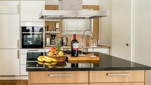 A modern kitchen with a black countertop, wooden cabinets, and a built-in oven. - Holiday Home Huus Adele (Holzminden)