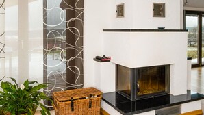 A modern living room with a fireplace, a large window, and a decorative wall panel. - Holiday Home Huus Adele (Holzminden)