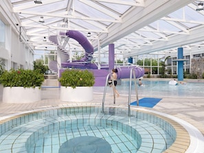 An indoor swimming pool with a slide and a water feature.