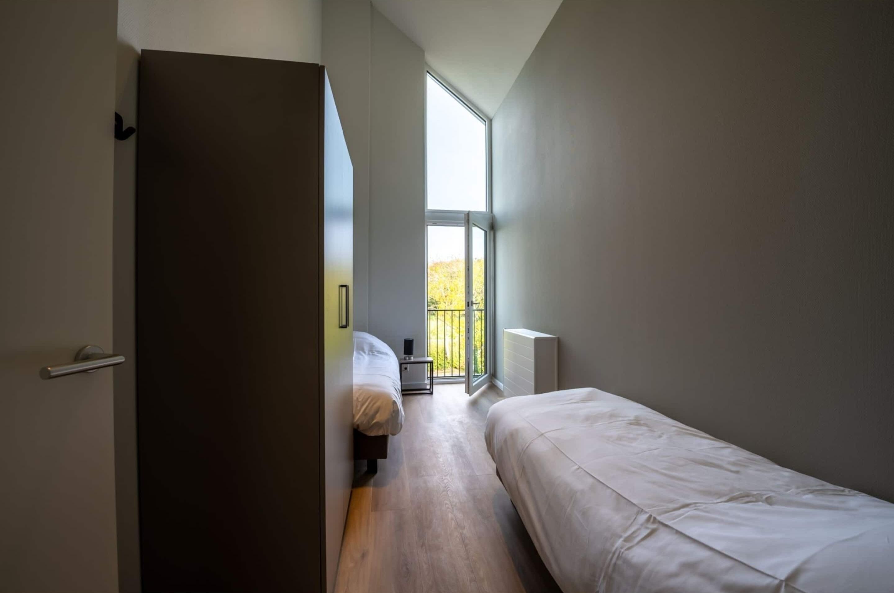 Ein modernes Schlafzimmer mit großem Fenster, einer Tür und einem kleinen Nachttisch.