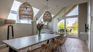 A dining area with a long table, wicker chairs, and a vase of flowers. - Stylish Marina Loft W/balcony (Kamperland)
