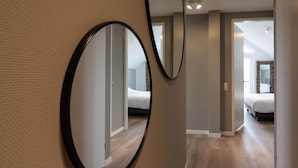 A hallway with a large mirror reflecting a bedroom with a bed and a window. - Stylish Marina Loft W/balcony (Kamperland)