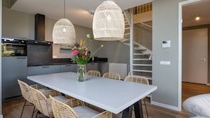 A modern kitchen with a white dining table, wicker chairs, and a vase of flowers. - Stylish Marina Loft W/balcony (Kamperland)