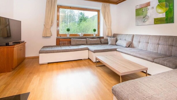 Ein modernes Wohnzimmer mit einer Eckcouch, einem Couchtisch und einem Fernseher auf einer Holzkommode.