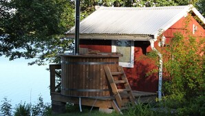Una cabaña rústica con terraza de madera, un jacuzzi y una escalera.