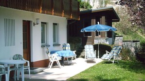 A patio with a table and chairs, a blue umbrella, and lounge chairs. - Huis Becker-schmidt, St. Blasien (St. Blasien)
