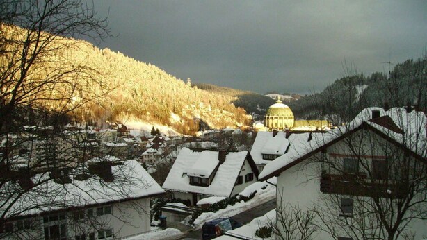 A snow-covered village with traditional houses and a prominent golden-domed building in the background. - Huis Becker-schmidt, St. Blasien (St. Blasien)