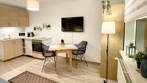 Una cocina moderna con comedor, televisor de pantalla plana y lámpara de pie.