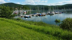 Un puerto deportivo con barcos amarrados, rodeado de vegetación y colinas.