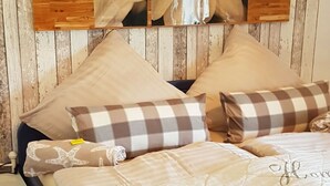 A bedroom with a wooden headboard, a bed with beige bedding, and multiple pillows, including a checkered one. - Apartment in Rieseby (Rieseby)