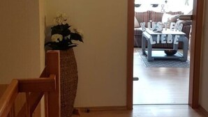 A hallway with a wooden staircase, a clock, and a plant. - Apartment in Rieseby (Rieseby)