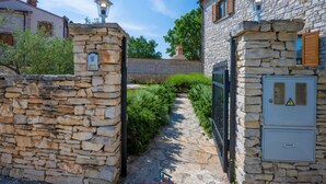 Un camino de piedra que lleva a una entrada con puerta y una pared de piedra, además de un farol.