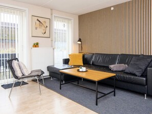 A modern living room with a sofa, a coffee table, a chair, and a radiator. - 4 Star Holiday Home in Romo (Rømø)