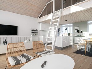 A modern loft apartment with a loft bed, a kitchen, and a dining area. - 8 Person Holiday Home on a Holiday Park in Lokken (Lokken)