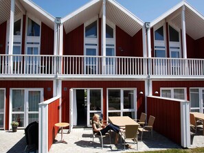 A red building with white trim, featuring a balcony with white railings and multiple windows. - 8 Person Holiday Home on a Holiday Park in Lokken (Lokken)