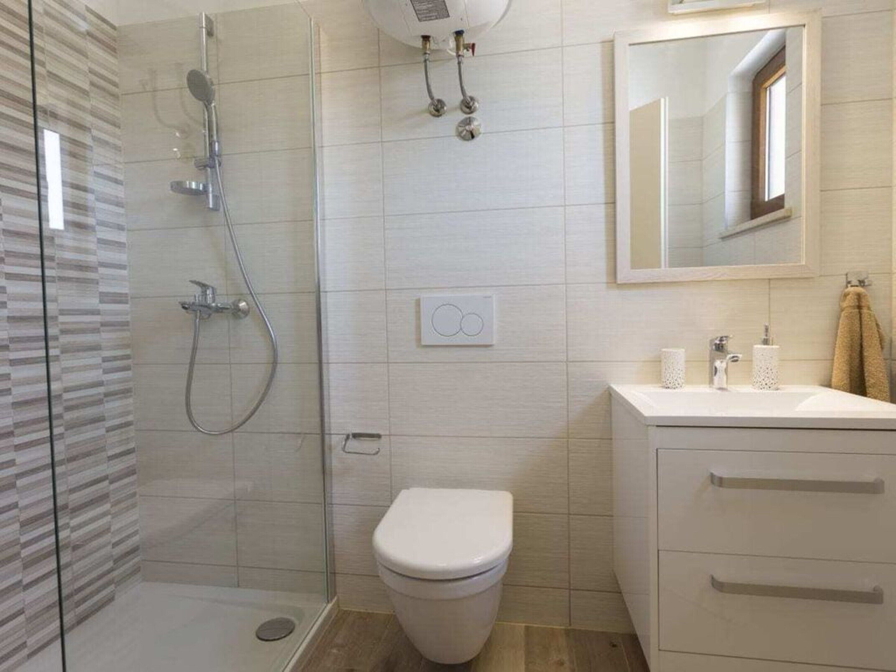 A bathroom with a glass-enclosed shower, a toilet, a sink with a mirror, and a towel rack.