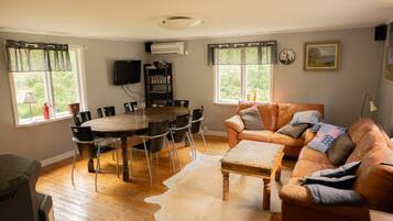 A living room with a round wooden table, leather sofa, and a white cowhide rug.
