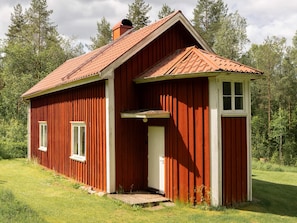 A red wooden cabin with a sloped roof, a front door, and a small porch. - 6 Person Holiday Home in Sandhult (Sandhult)