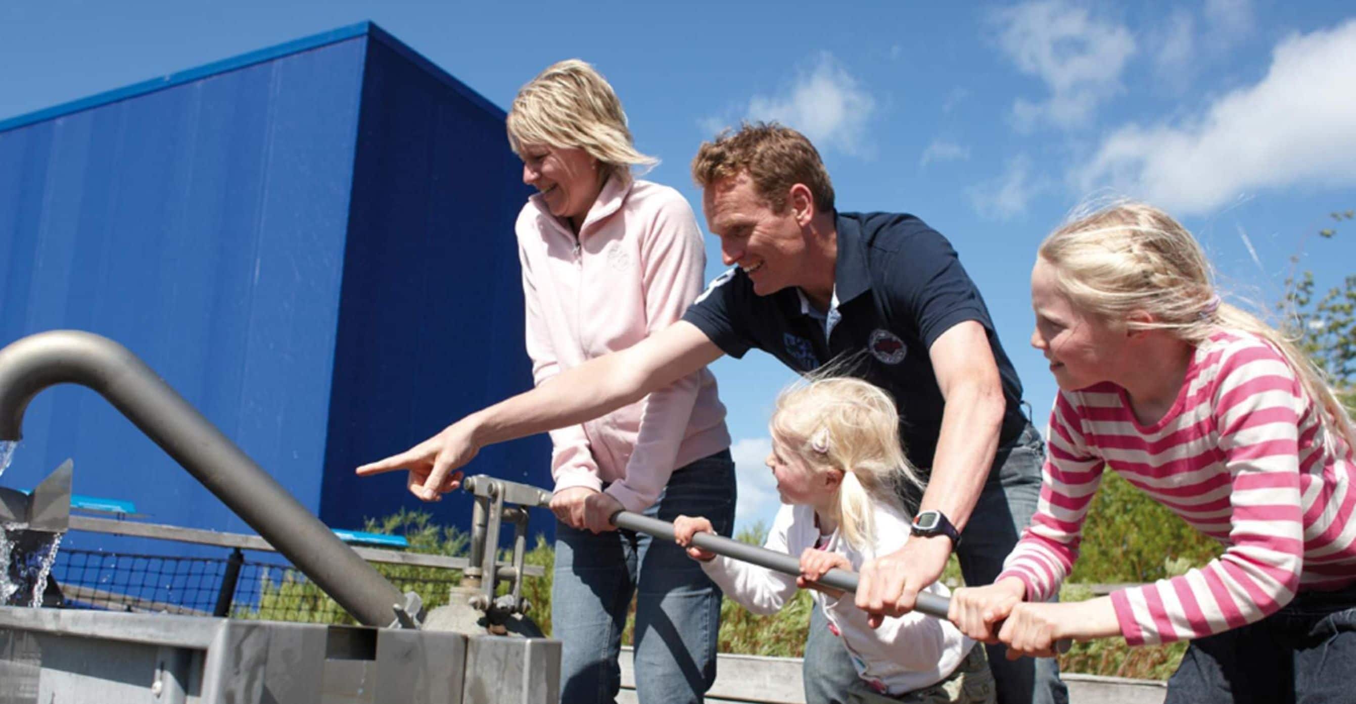 A group of people using a water pump outdoors.