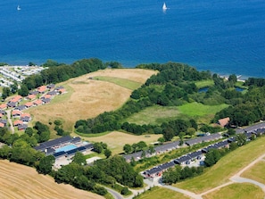 Vue aérienne d’un quartier résidentiel situé sur la côte, avec des maisons, une piscine et un port de plaisance.