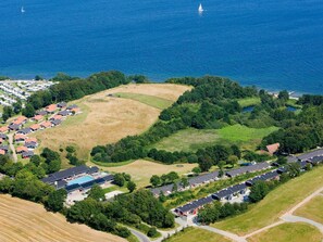 An aerial view of a coastal residential area with houses, a swimming pool, and a marina.
