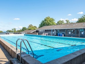A swimming pool with a lifeguard station, lounge chairs, and a covered seating area. - 5 Person Holiday Park Home in Aabenraa (Aabenraa)