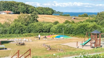 A park with picnic tables, a playground, and a view of the sea.