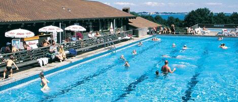A swimming pool with multiple lanes, spectators, and umbrellas.