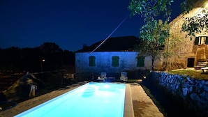 A swimming pool with a stone wall and a stone building in the background.