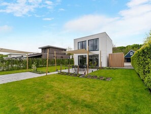 A modern house with a patio, a garden, and a neighboring building. - Amazing Villa in Zeewolde With Terrace (Zeewolde)