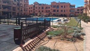 Un ensemble immobilier résidentiel comprenant une piscine, un jardin clos et une allée piétonne dallée.