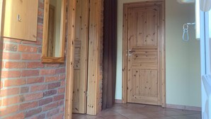 Un couloir avec des portes en bois, un miroir et une pancarte de bienvenue.