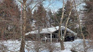 Una cabaña cubierta de nieve rodeada de árboles.