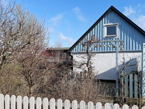 A blue building with a white picket fence in the foreground. - 4 Person Holiday Home in Tomelilla (Tomelilla)