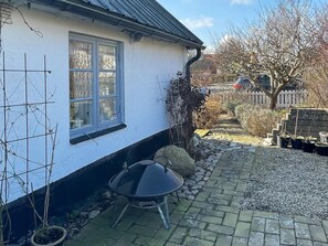 A white house with a window, a black grill, and a stone pathway leading to a gate. - 4 Person Holiday Home in Tomelilla (Tomelilla)