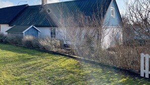 Una casa con tetto spiovente, un camino e un recinto di legno bianco.
