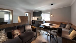 Een modern interieur met een donkerbruine bank, een houten eettafel en een keukenhoek.