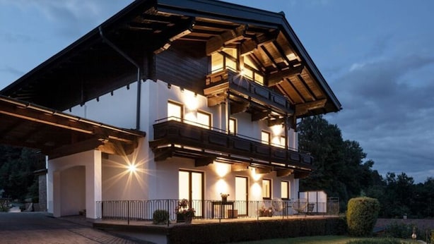 Een modern huis met twee verdiepingen, een balkon en een goed verlichte entree.