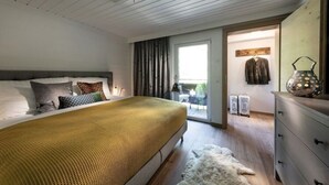Een slaapkamer met een groot bed, een ladekast, een raam met gordijnen en uitzicht op het omliggende landschap.