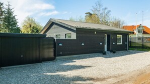 A modern two-story building with a dark exterior, a sloped roof, and a gravel driveway. - 4 Star Holiday Home in Vaeggerlose (Vaeggerlose)