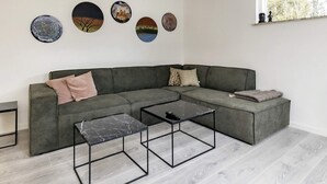 A modern living room with a grey sectional sofa, two black coffee tables, and four circular wall art pieces. - 4 Star Holiday Home in Vaeggerlose (Vaeggerlose)